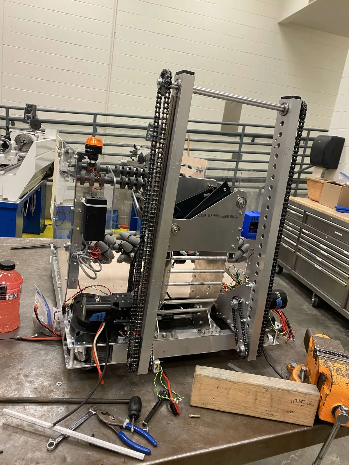 The assembled climbing mechanism on a workbench, showing linear rails, chain runs, and hooks