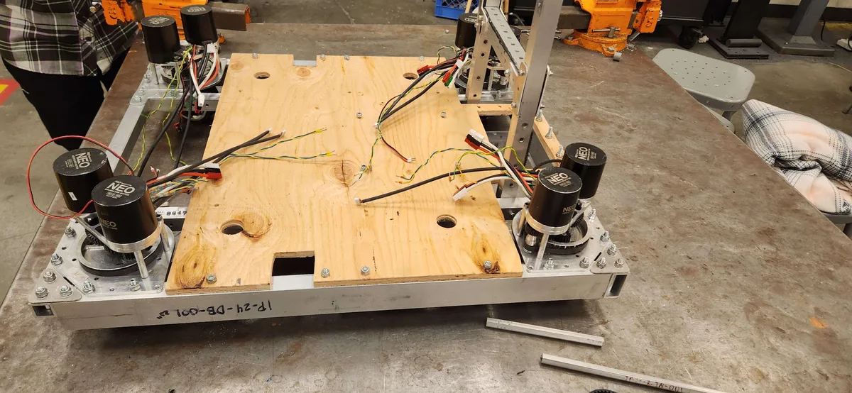 The chassis during assembly with four swerve modules mounted and wiring routed under the bellypan